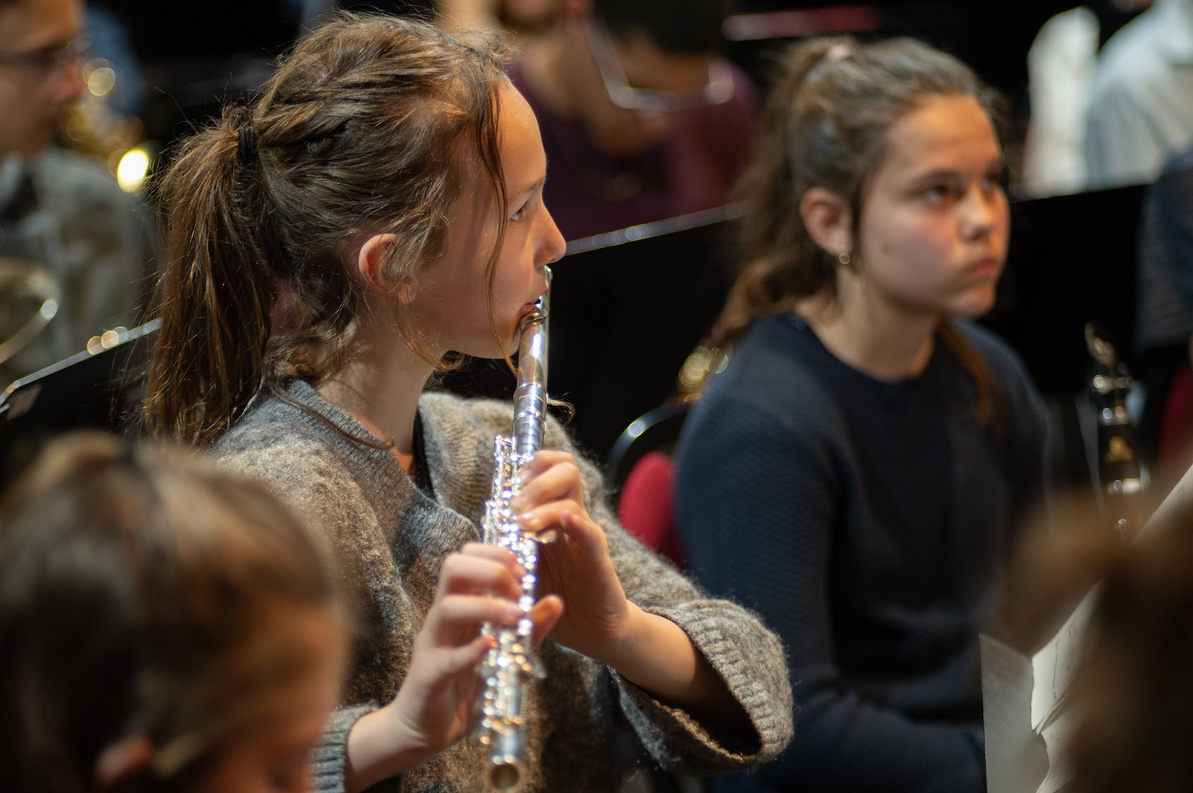 Deux jeunes filles jouant de la flute au milieu d'un orchestre
